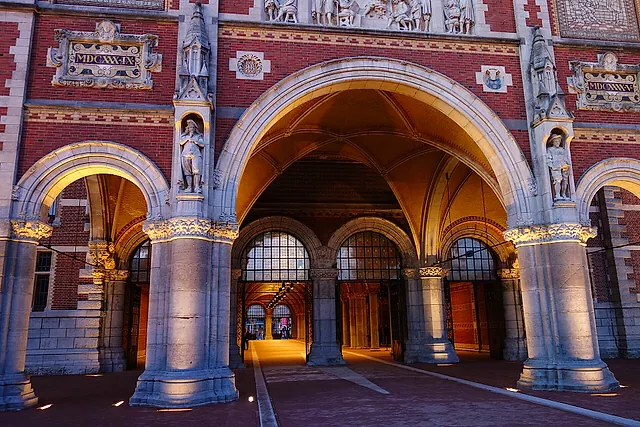 The main entrance arch of the Rijksmuseum, with brick and stone decoration and statues, lit warmly